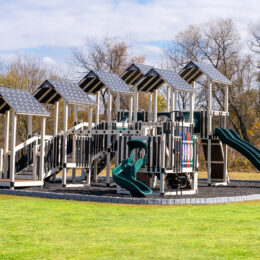 A commercial playground with slides sitting in mulch bed.