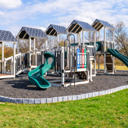 A commercial playground with slides sitting in mulch bed.