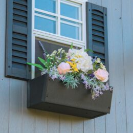 A flowerbox on a vinyl playhouse. It is filled with flowers.